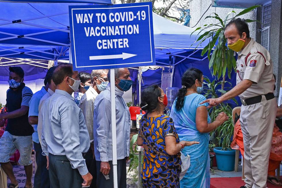 Folk venter i kø for å motta første dose av vaksinen mot covid-19 på et vaksinesenter i New Delhi i India, 10. april.