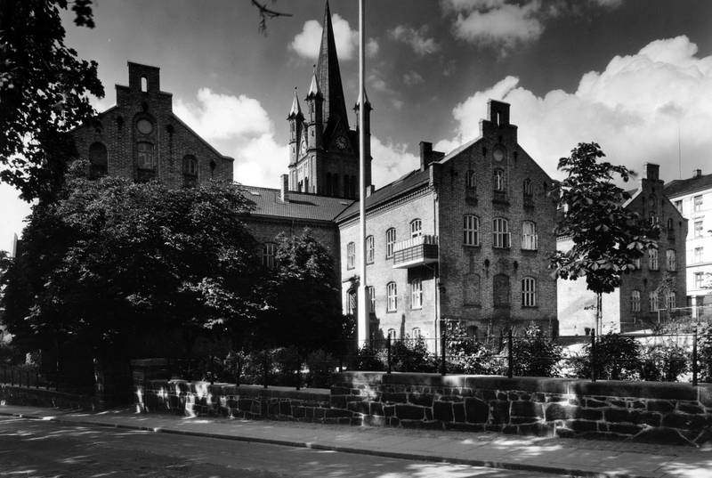 Oslo kommunale husmorskole ble opprettet i 1917, og flyttet inn i Borggata 2b på Grønland i 1930. Foto av skolebygningen i Borggata i 1937. Tårnet på Grønland kirke i bakgrunnen.