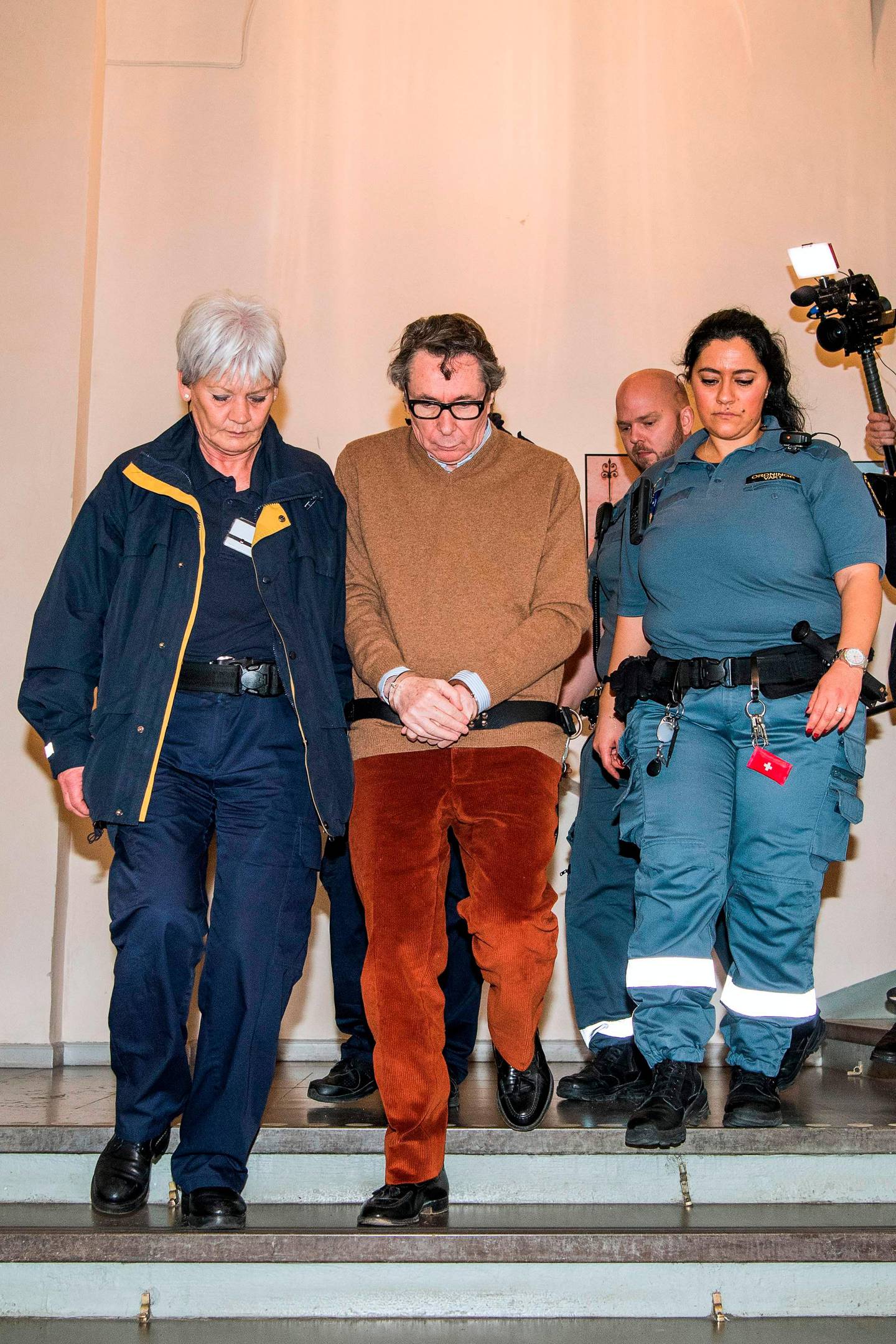 Frenchman Jean-Claude Arnault (C) is escorted out after the first day of his appeal trial on November 12, 2018 in Stockholm. - An appeals trial opens in Stockholm on Monday for a Frenchman jailed two years for rape in a scandal that led to the postponement of this year's Nobel Literature Prize. Once an influential figure in Stockholm's cultural scene, 72-year-old Jean-Claude Arnault was found guilty in October of raping a young woman in 2011 and sentenced to two years in prison. (Photo by Jonathan NACKSTRAND / AFP)