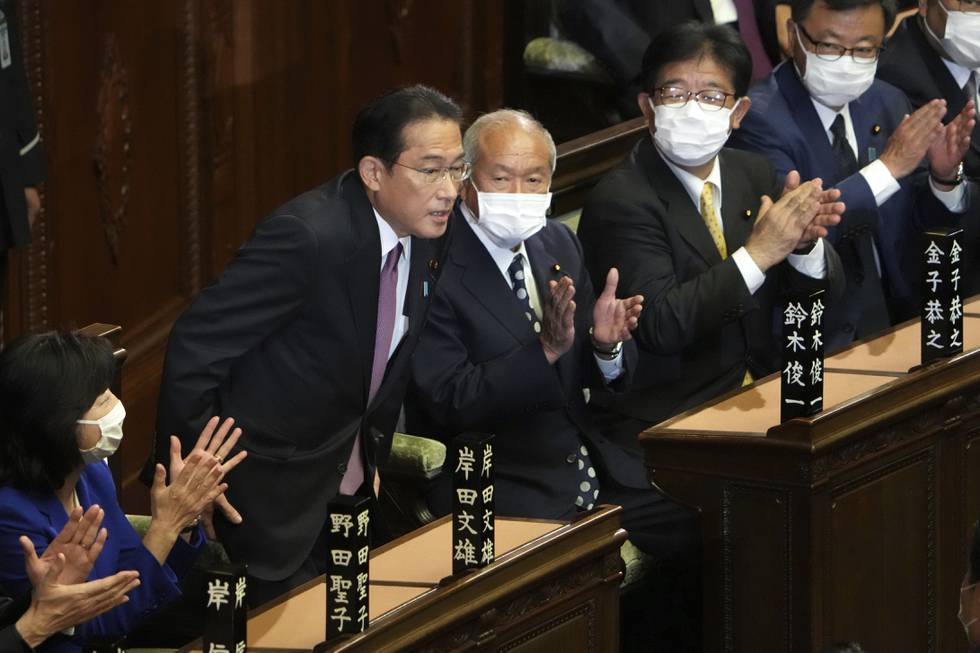 Fumio Kishida (i midten) bukker etter at han ble gjenvalgt som Japans statsminister  tiende november 2021.