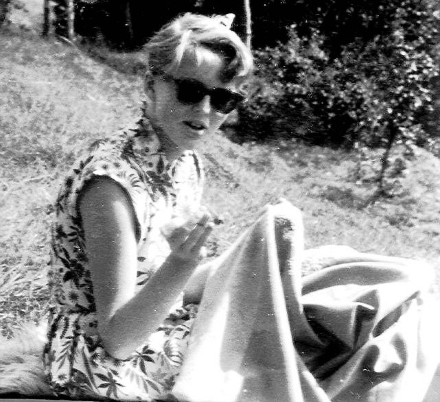Astrid drømte om kjøpegenser perlekjede, men måtte stort sett sy klærne sine selv. Her sitter hun på hytta og syr på bunaden sin - i hjemmesydd sommerkjole. Foto: Hilde Unosen