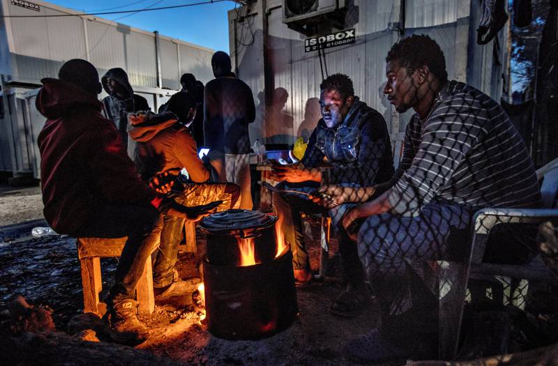 Unge menn fra Mali utenfor de såkalte Isoboksene, konteinerne som er overfylt av flyktninger i Moria-leiren. Flyktninger krysser fortsatt Egeerhavet på flukt fra krig og uroligheter hjemme. De blir flyktninger i sorgens Moria.