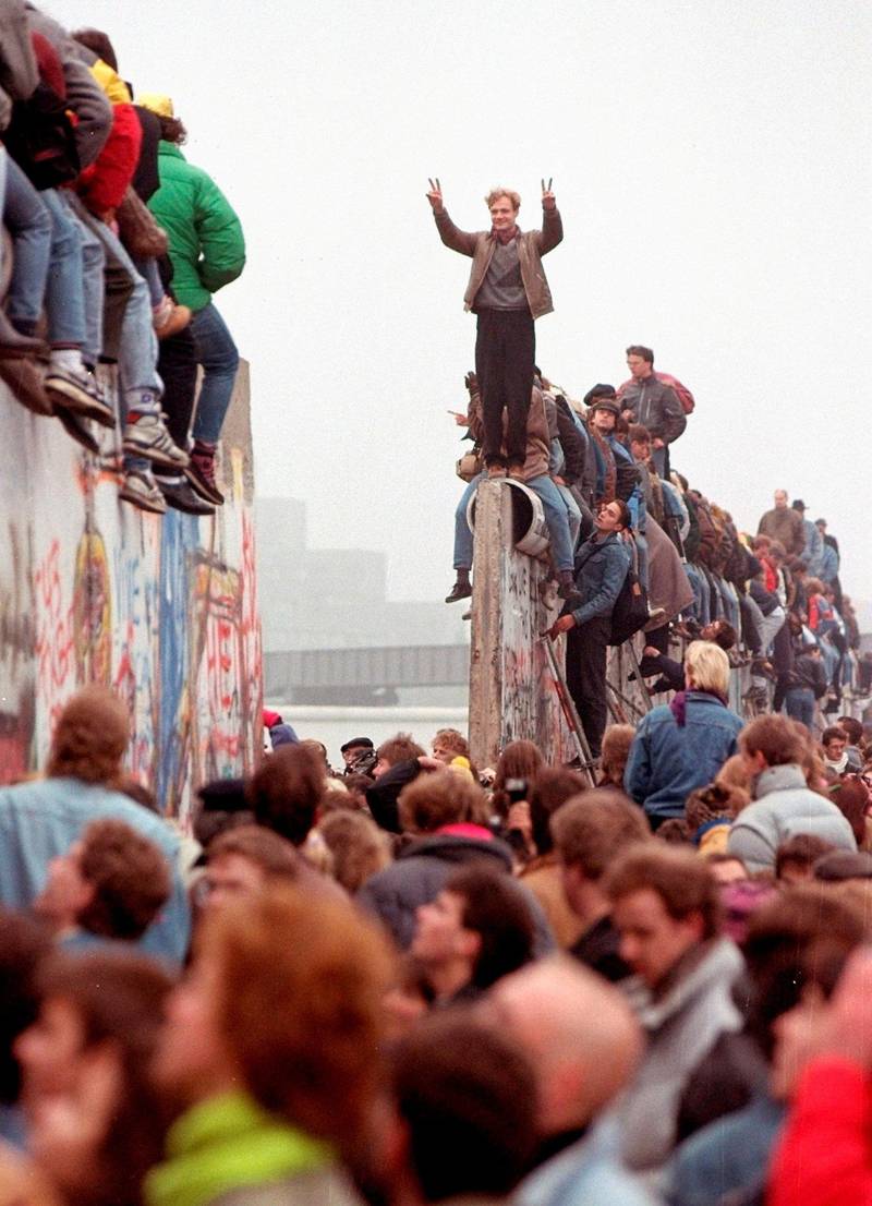 Feiring på toppen av muren ved Potsdamer Platz, mens østtyskere strømmer over grensen. Foto: Lionel Cironneau/ap/ntb scanpix