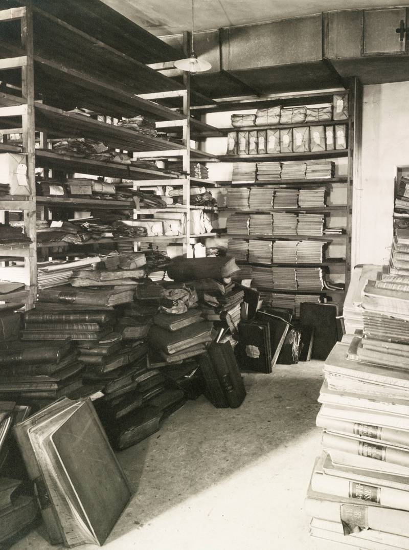 Interiørfoto fra kommunearkivet i Gamle Logen med stabler av kommunens arkivmateriale, 1916.
