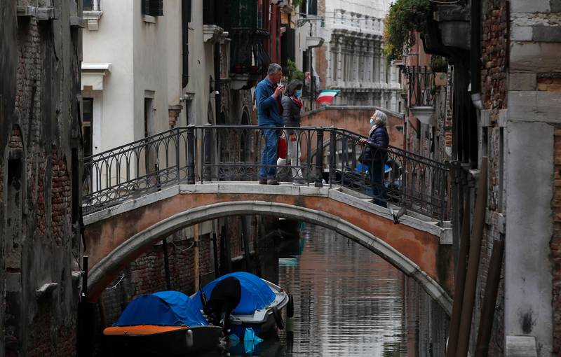 In this picture taken on Wednesday, May 13, 2020, people talk to each other on a bridge in Venice, Italy. Venetians are rethinking their city in the quiet brought by the coronavirus pandemic. For years, the unbridled success of Venice's tourism industry threatened to ruin the things that made it an attractive destination to begin with. Now the pandemic has ground to a halt Italys most-visited city, stopped the flow of 3 billion euros in annual tourism-related revenue and devastated the city's economy. (AP Photo/Antonio Calanni)