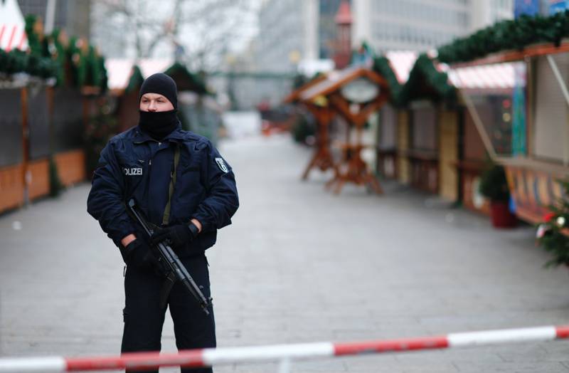 En politimann holder vakt ved markedet i Vest-Berlin, der tolv mennesker ble drept mandag kveld. Tunisieren Anis Amir er ettersøkt. 