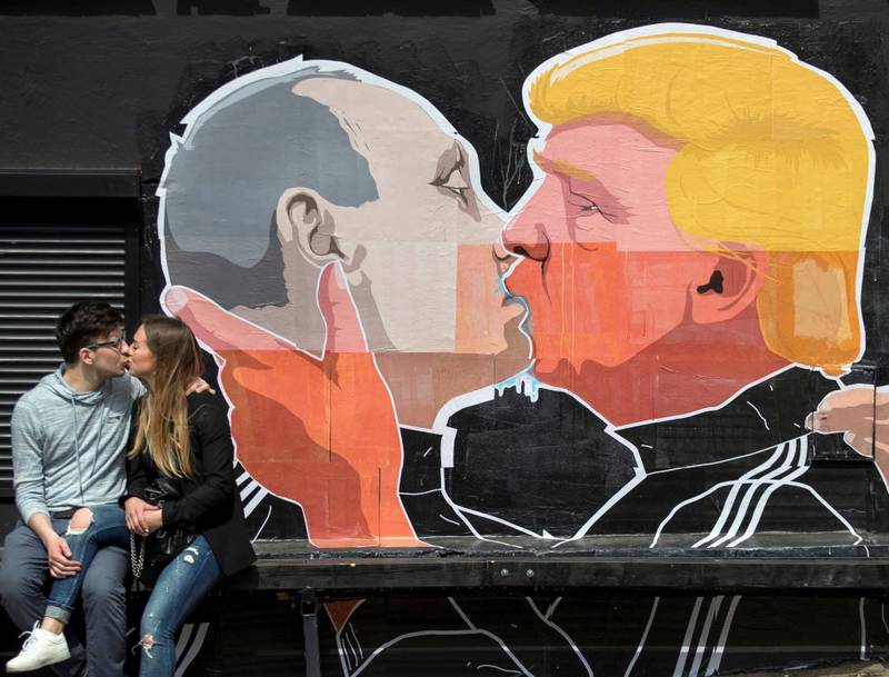 NÆR RELASJON?: Et par kysser foran et grafittimaleri av Russlands og USAs president i Litauen. Spekulasjonene rundt forbindelser mellom Trump-administrasjonen og Russland har gått helt siden valget. FOTO: MINDAUGUS KULBIS/NTB SCANPIX