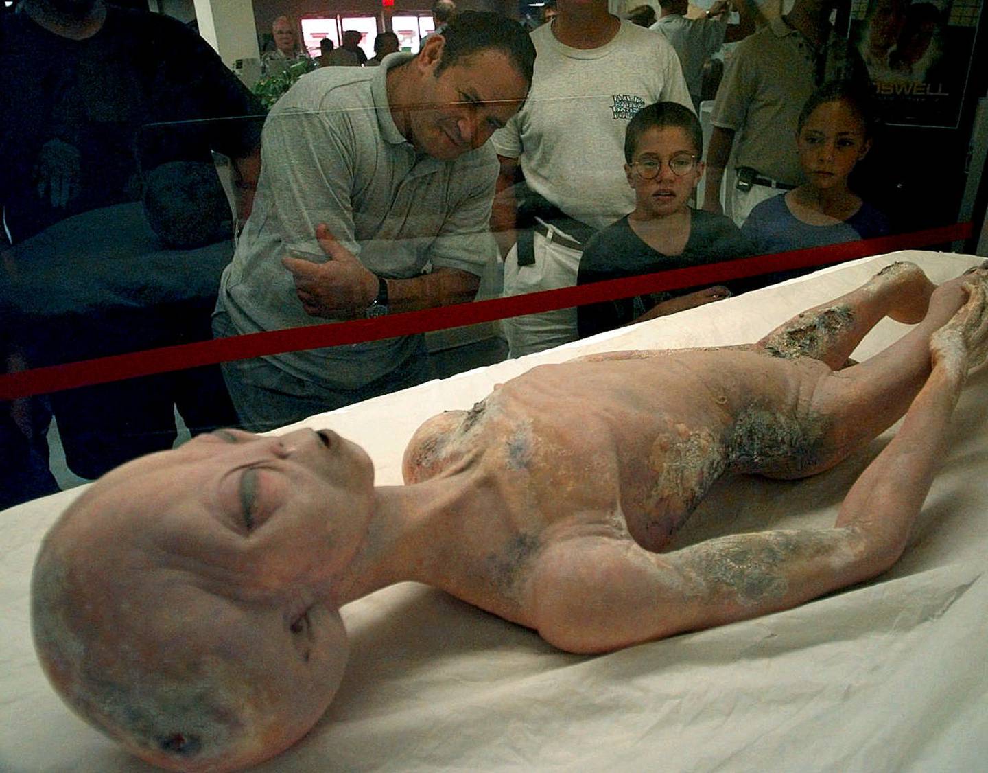Visitors to the International UFO Museum in Roswell, New Mexico examine a glass-encased alien prop used in the movie "Roswell" Wednesday, July 2, 1997. Over 2,000 visitors walked through the museum Monday as tourists began to pour into town for the 50th anniversary of the Roswell incident. (AP Photo/Susan Sterner)