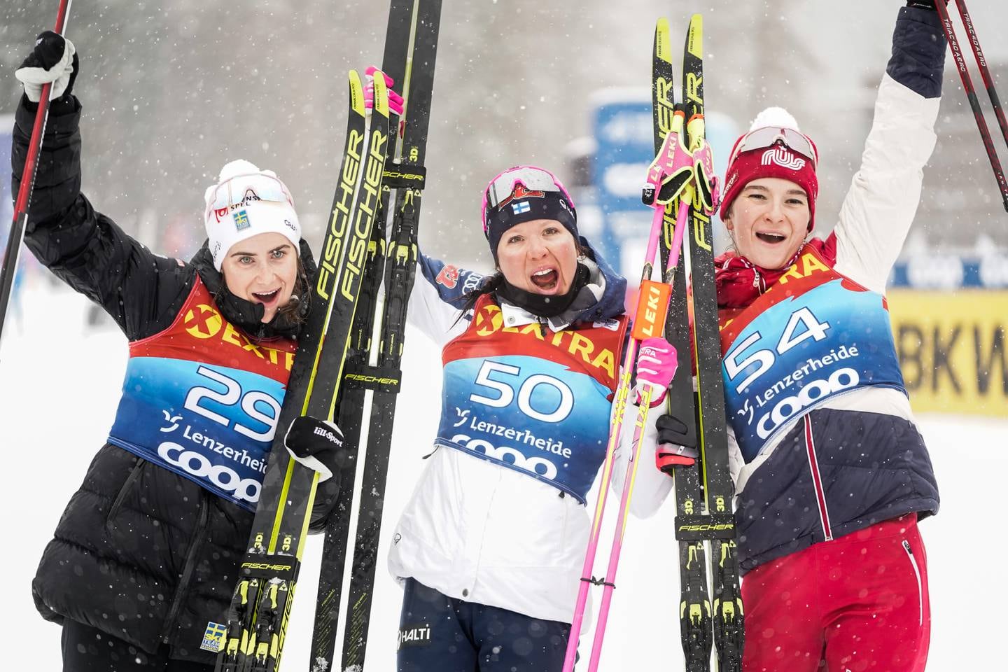 Finske Kerttu Niskanen jubler etter seier på 10 km klassisk for kvinner  under Tour de Ski i Lenzerheide. Ebba Andersson (t.v.) kom på 2. plass og russiske Natalia Neprjajeva kom på 3. plass.