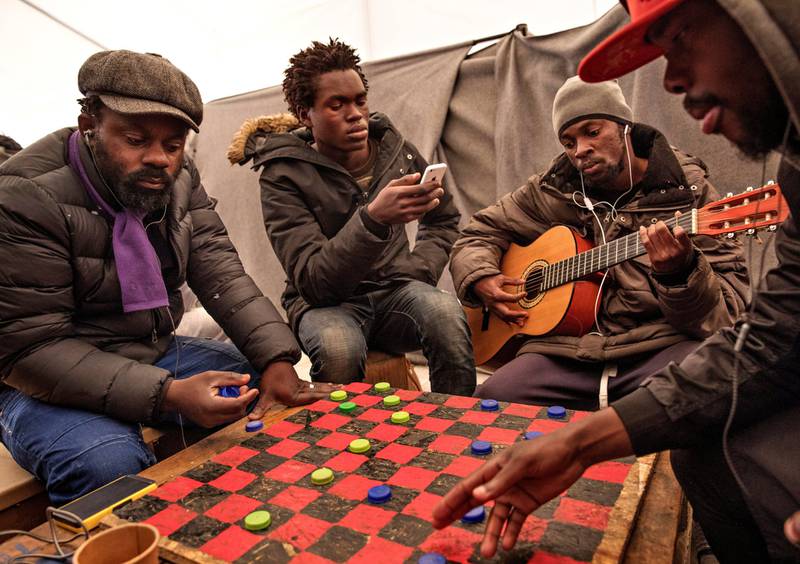 Over 100 unge menn bor i et stort telt i Olive Grove Camp. Her spiller unge kongolesere dam med hjemmelagde brikker på en gammel sponplate. Romeo (til høyre) vinner mest