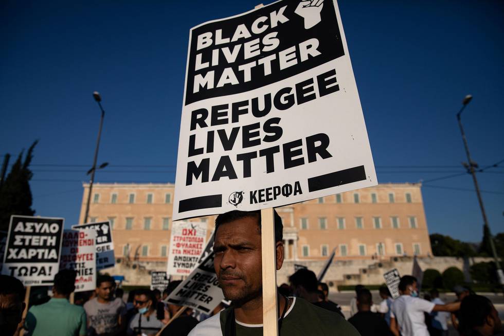 A migrant holds a placard reading "Black Lives Matter, Refugee Lives Matter" during a demonstration outside the Greek parliament against a government decision that refugees staying in apartments funded by a European Union and UNHCR programme should leave their accommodation, in Athens, Greece, June 26, 2020. REUTERS/Alkis Konstantinidis