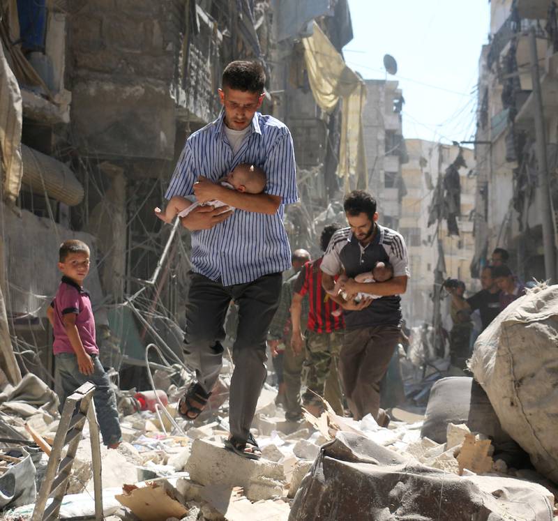 Menn i et opprørskontrollert område nord i Aleppo flykter med babyer etter bombeangrep over byen.