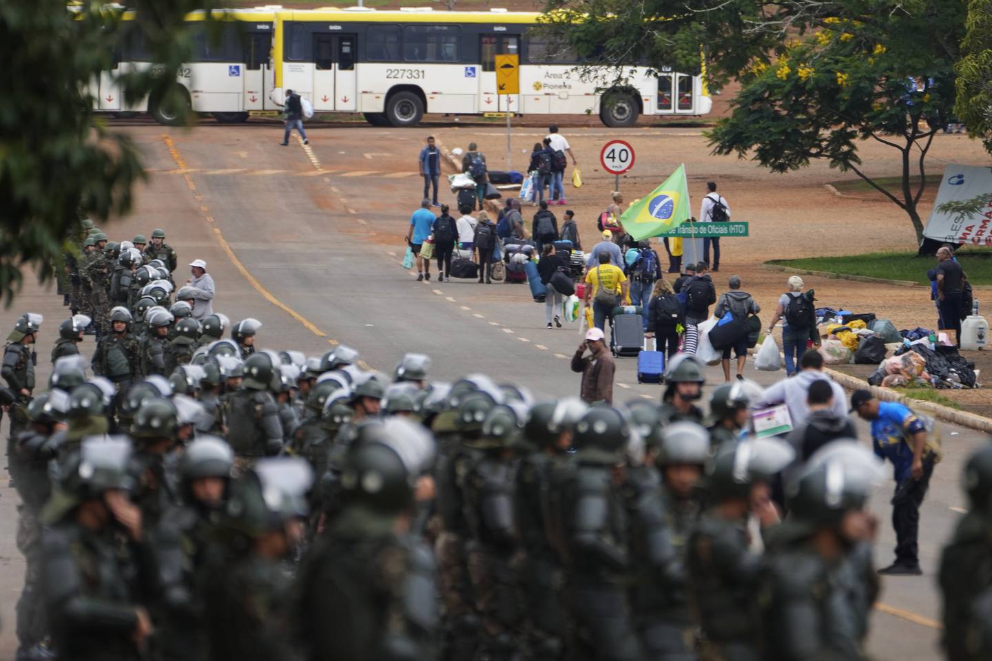 Politibetjenter holder vakt mens Bolsonaro-tilhengere forlater en leir i Brasilia mandag.