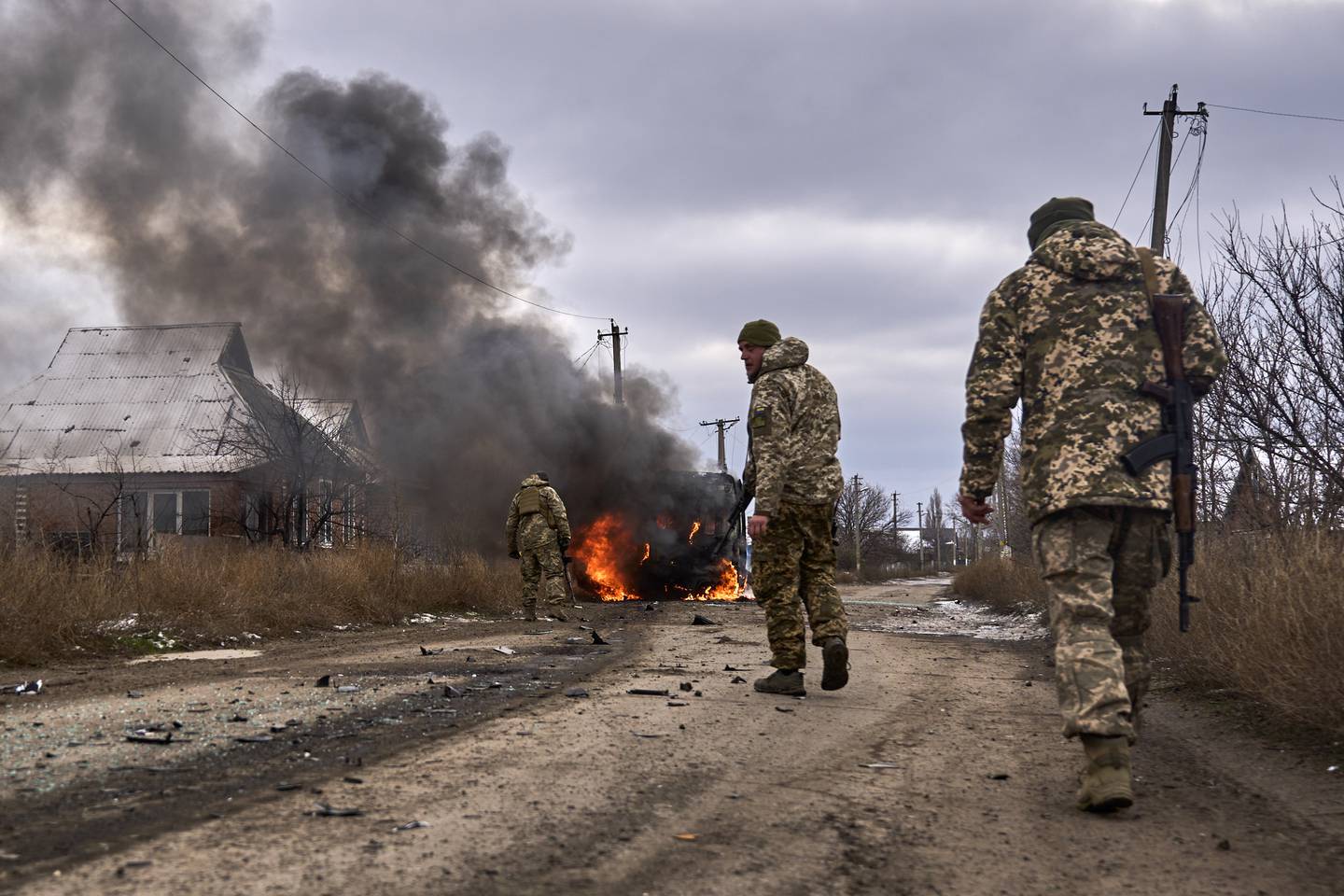 FILE - In this photo provided by the Ukrainian 10th Mountain Assault Brigade "Edelweiss", Ukrainian soldiers pass by a volunteer bus burning after a Russian drone hit it near Bakhmut, Donetsk region, Ukraine, Thursday, Nov. 23, 2023. A gloomy mood hangs over Ukraine’s soldiers nearly two years after Russia invaded their country. Ukrainian soldiers remain fiercely determined to win, despite a disappointing counteroffensive this summer and signs of wavering financial support from allies. (Shandyba Mykyta, Ukrainian 10th Mountain Assault Brigade "Edelweiss" via AP, File)