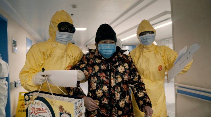 An elderly woman with COVID-19, center, is escorted by two nurses after being admitted to a hospital in Wuhan, China in a scene from the documentary "76 Days." The film, shot in four Wuhan hospitals, captures a local horror before it became a global nightmare. Given the constraints at the time on footage and information from Wuhan, it's a rare window into the infancy of the pandemic. (MTV Documentary Films via AP)