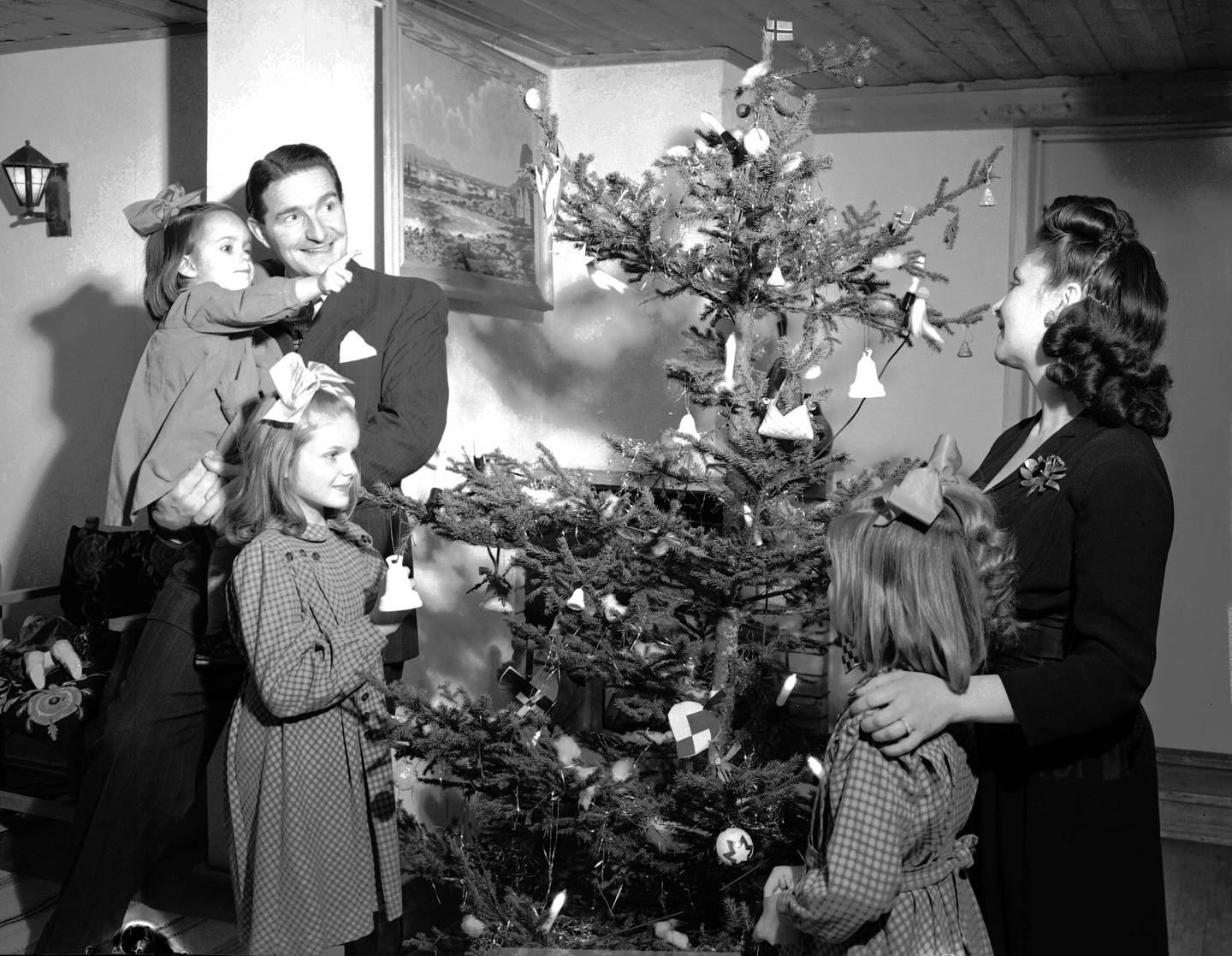OSLO 19490105 Artisten Jens Book Jenssen med familie feirer jul. Interiør fra stuen, familien står rundt juletreet. Gammeldags uregelmessig juletre.
Foto:  NTB / NTB