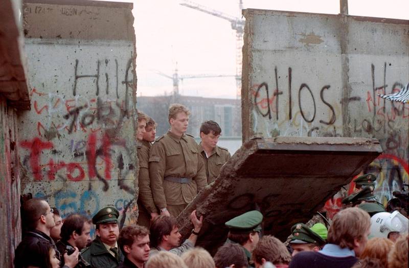 Østtyske grensevakter og demonstranter like etter at sistnevnte har revet ned en del av Berlinmuren i november 1989.  foto: Lionel Cironneau/ap/ ntb scanpix