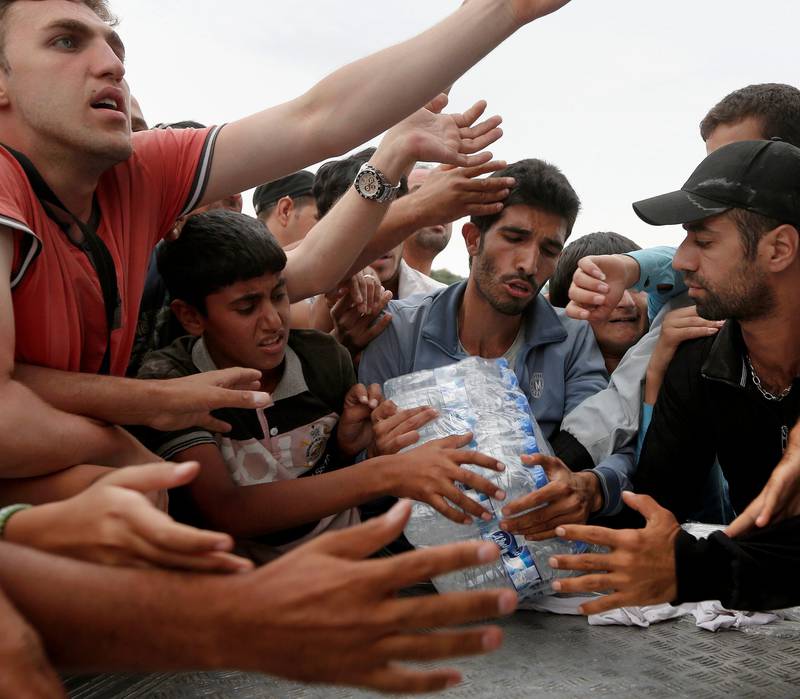 Flyktninger og migranter kjemper om drikke på grensen mellom Hellas og Makedonia. FOTO: NTB SCANPIX