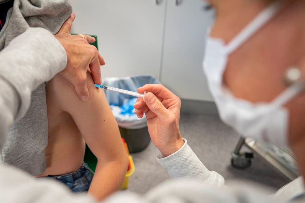 En gutt blir vaksinert i armen av en sykepleier, illustrasjonsbilde