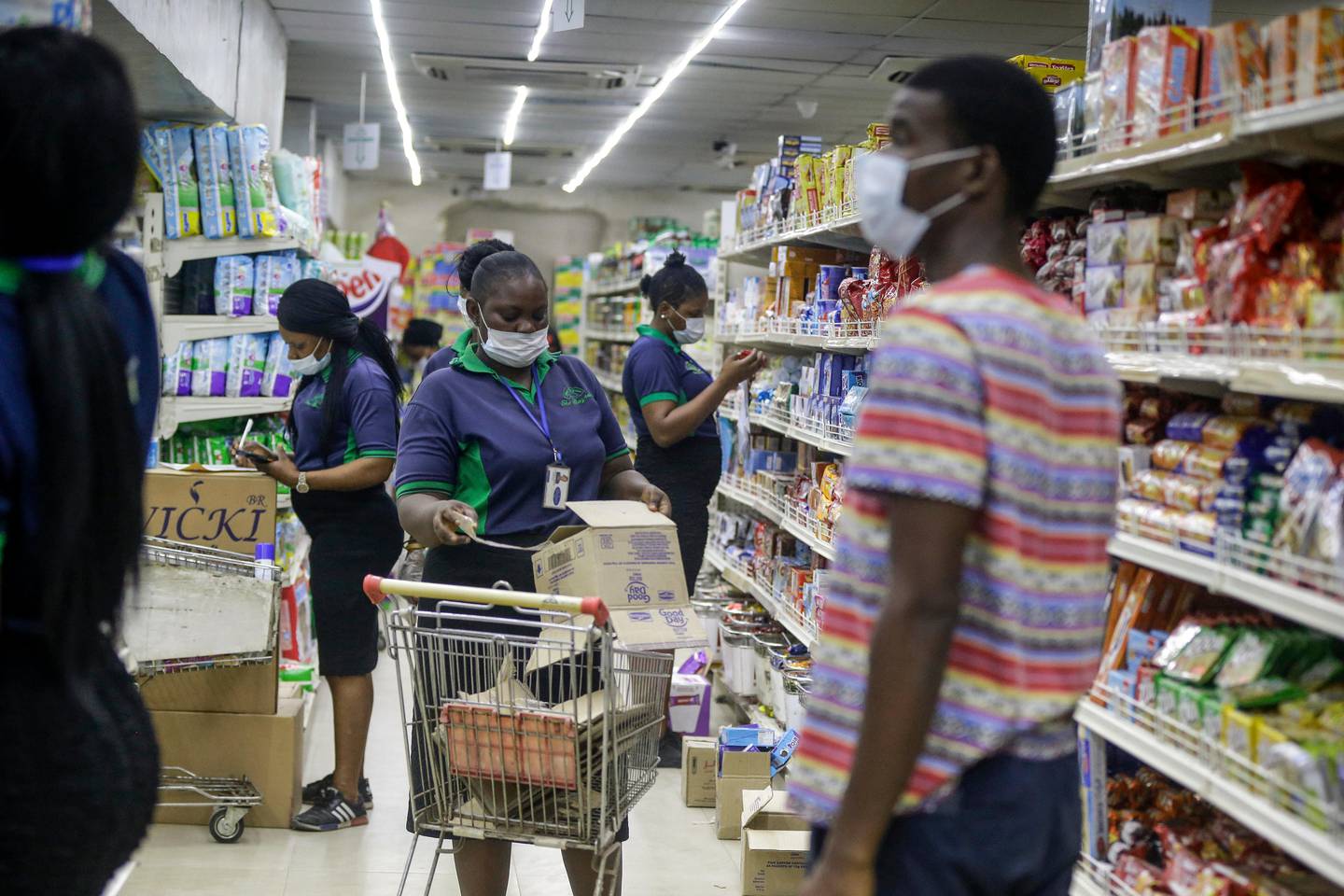 Shop assistants wearing face masks to prevent against the spread of the new coronavirus take stock in a supermarket in Lagos, Nigeria Friday, March 27, 2020. The new coronavirus causes mild or moderate symptoms for most people, but for some, especially older adults and people with existing health problems, it can cause more severe illness or death. (AP Photo/Sunday Alamba)