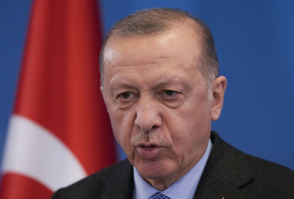 Bildet er et nærbilde av Recep Erdogan. Han står foran en blå vegg. I bakgrunnen er et tyrkisk flagg. Det er rødt, med en hvit halvmåne og stjerne. Foto: Markus Schreiber / AP / NTB
