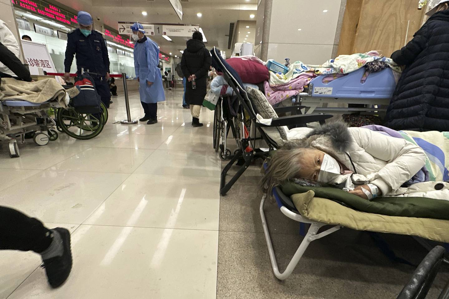 Elderly patients rest in an area cordoned off to provide intravenous drips at a hospital in Beijing, Saturday, Dec. 31, 2022. China is on a bumpy road back to normal life as schools, shopping malls and restaurants fill up again with the easing of COVID-19 restriction. The abrupt end to testing and other measures came as hospitals were swamped with feverish, wheezing COVID-19 patients (AP Photo/Ng Han Guan)