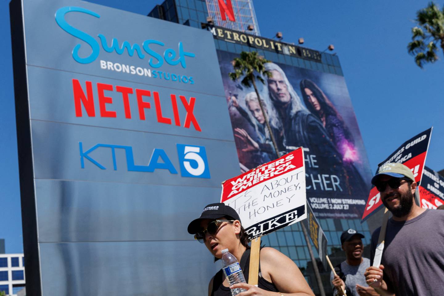 Den amerikanske manusforfatterforeningen,  Writers Guild of America (WGA), deltar også i streiken. Her foran Netflix sitt kontor i Los Angeles 12 juli. På et av skiltene står det: "It's about the money, honey".