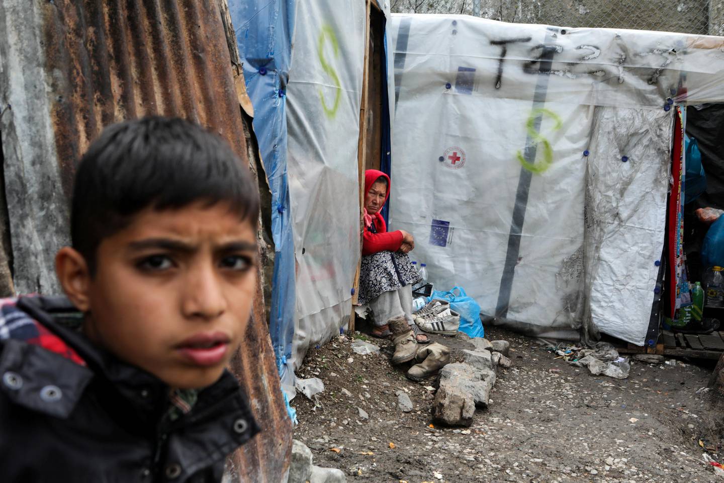 FILE PHOTO: Migrants stand outside a temporary shelter in a makeshift camp for refugees and migrants next to the Moria camp, during a nationwide lockdown to contain the spread of the coronavirus disease (COVID-19), on the island of Lesbos, Greece April 02, 2020. REUTERS/Elias Marcou/File Photo