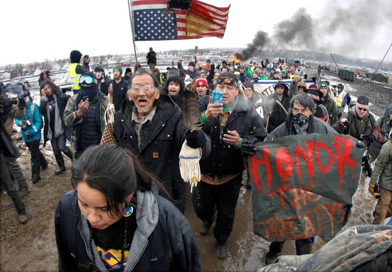 URFOLK OG KLIMA: Protestanter marsjerer ut fra campen de har bodd i flere måneder i protest mot oljerørledningen Dakota Access. FOTO: NTB SCANPIX