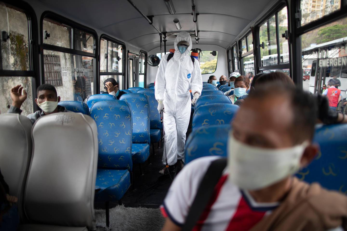 A city worker sprays a disinfectant in the aisle of a bus as a measure to curb the spread of the new coronavirus in Caracas, Venezuela, Tuesday, April 21, 2020. (AP Photo/Ariana Cubillos)