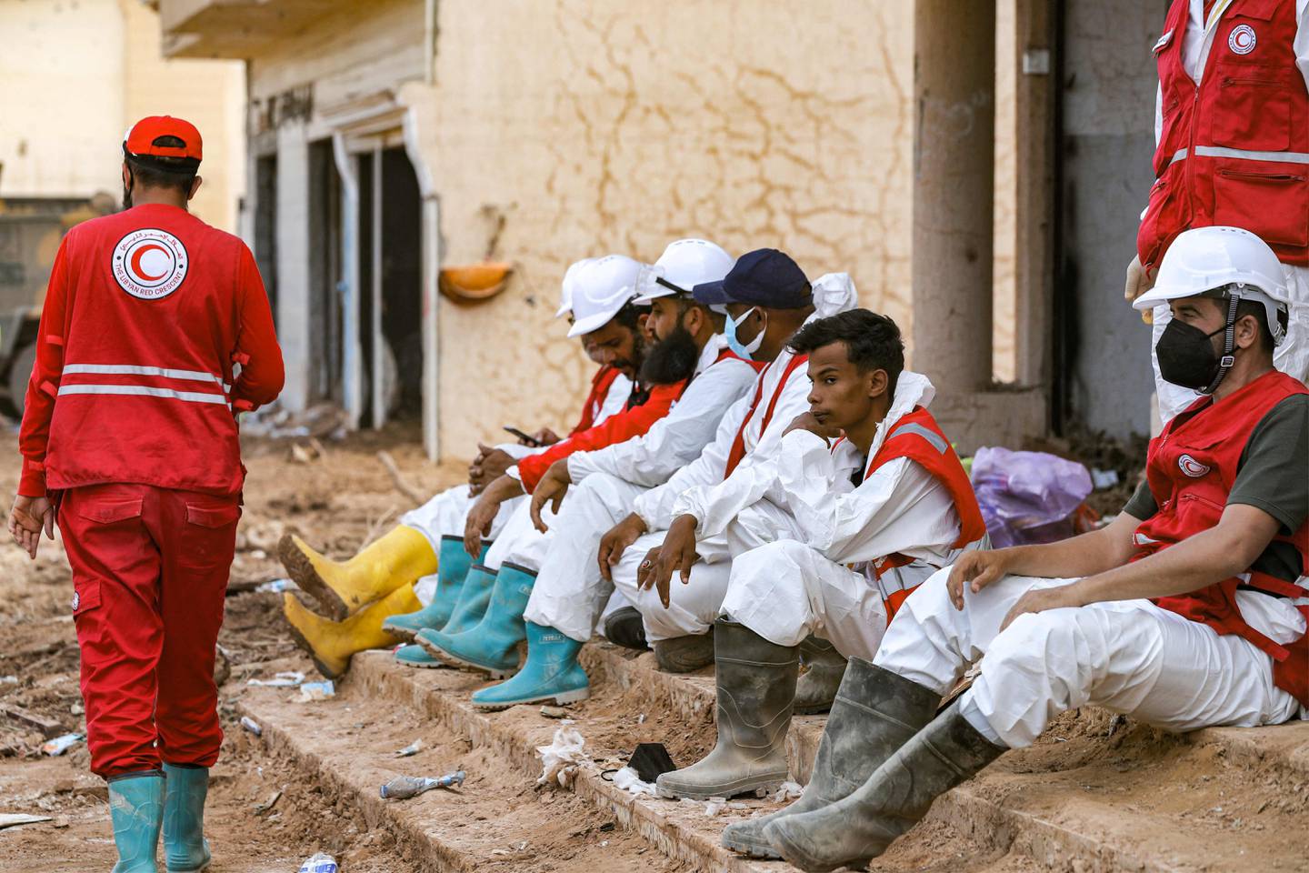Rescue teams sit in Libya's eastern city of Derna on September 18, 2023, following deadly flash floods.  A week after a tsunami-sized flash flood devastated the Libyan coastal city of Derna, sweeping thousands to their deaths, the international aid effort to help the grieving survivors slowly gathered pace.  The enormous flood, fueled by torrential rains on September 10, had broken through two upstream dams and sent a giant wave crashing down the previously dry river bed, or wadi, that bisects the city of about 100,000 people.  (Photo by Mahmud Turkey / AFP)