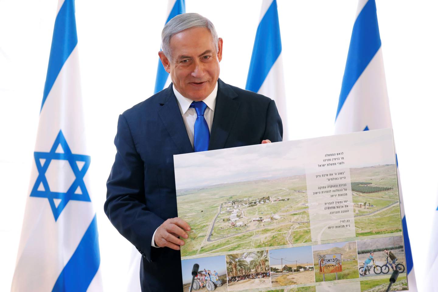 Israeli Prime Minister Benjamin Netanyahu holds up a placard given to him as a gift from Israeli residents of the area, at the start of a weekly cabinet meeting being held in a makeshift tent in the Jordan Valley, in the Israeli-occupied West Bank, Sunday, Sept. 15, 2019. Netanyahu convened his final pre-election cabinet meeting in a part of the West Bank that he's vowed to annex if re-elected. National elections are on Tuesday. (Amir Cohen/Pool via AP)