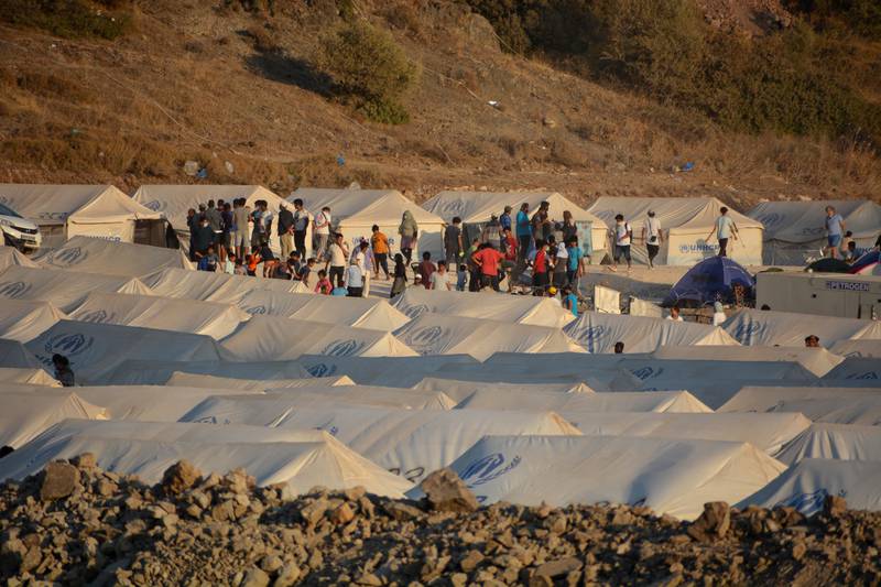 Migrants are seen inside the new temporary refugee camp in Kara Tepe, on the northeastern island of Lesbos, Greece, Saturday, Sept. 19, 2020. Police on the Greek island of Lesbos on Friday resumed relocating migrants rendered homeless when fires ravaged the country's largest refugee camp amid a local COVID-19 outbreak. (AP Photo/Panagiotis Balaskas)