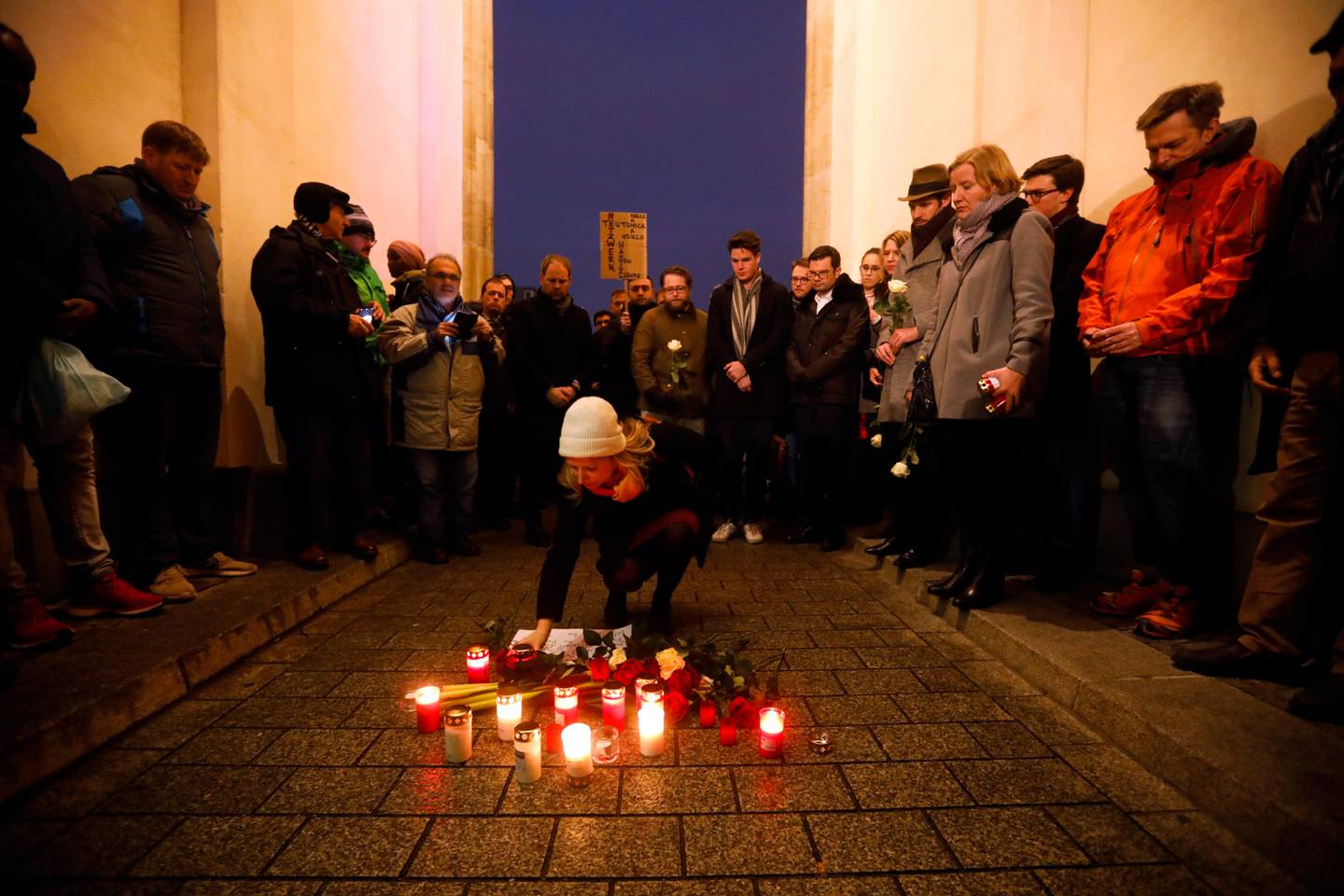 A woman lays down a candle during a vigil for victims of last night's shooting in the central German town Hanau, in front of the Brandenburg Gate in Berlin, Germany, Thursday, Feb. 20, 2020. A 43-year-old German man who posted a manifesto calling for the "complete extermination" of many "races or cultures in our midst" shot and several people of foreign background on Wednesday night, most of them Turkish, in an attack on a hookah bar and other sites in a Frankfurt suburb, authorities said Thursday. (AP Photo/Markus Schreiber)