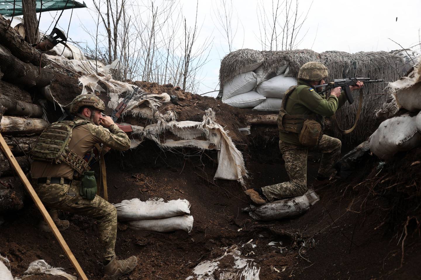 (FILES) Ukrainian soldiers shoot with assault rifles in a trench on the front line with Russian troops in Lugansk region on April 11, 2022. (Photo by Anatolii STEPANOV / AFP)