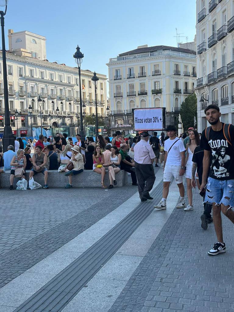 En mann bærer skiltet "Ricos Votan 30%" (Rike stemmer 30 prosent) i Madrid fredag kveld.