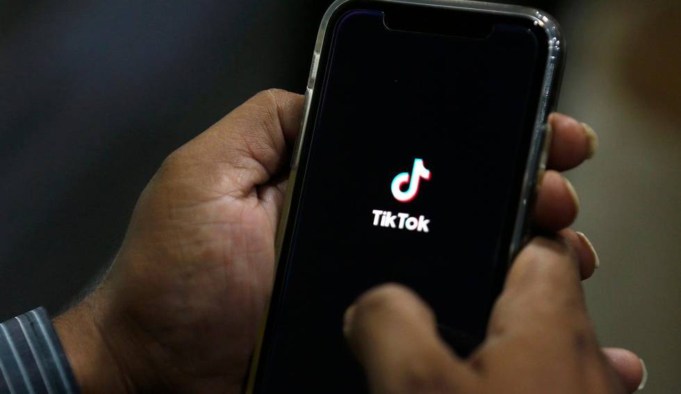 FILE - In this July 21, 2020 file photo, a man opens social media app 'TikTok' on his cell phone, in Islamabad, Pakistan. Walmart said Thursday, Aug. 27,  that it's interested in teaming up with Microsoft to buy the U.S. business of TikTok, the popular Chinese video app.  (AP Photo/Anjum Naveed, File)