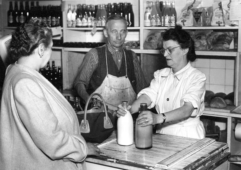 Ny og gammel melkeflaske i melkebutikken i Fagerborggata 54 i 1954. Innehaver Paulus Johansen var den siste av Fellesmeieriets ansatte som kjørte med hest.
