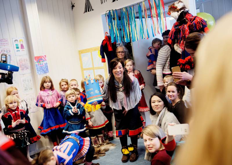 Styreleder Mari Helander overrekker bursdagskronen til Monica Mæland, mens barna synger bursdagssang. På samisk, selvsagt.