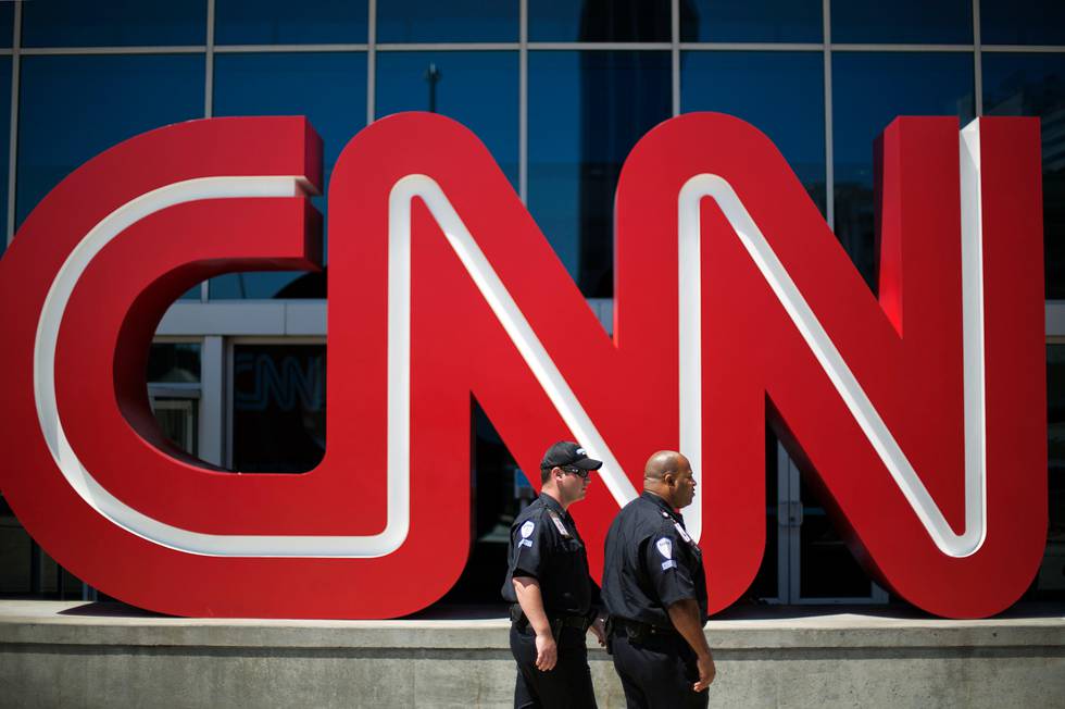 FILE - In this Aug. 26, 2014 file photo, security guards walk past the entrance to CNN headquarters in Atlanta. The international news channel on Tuesday, Nov. 11, 2014 announced it will halt broadcasting in Russia due to recent changes in media legislation. (AP Photo/David Goldman, File)