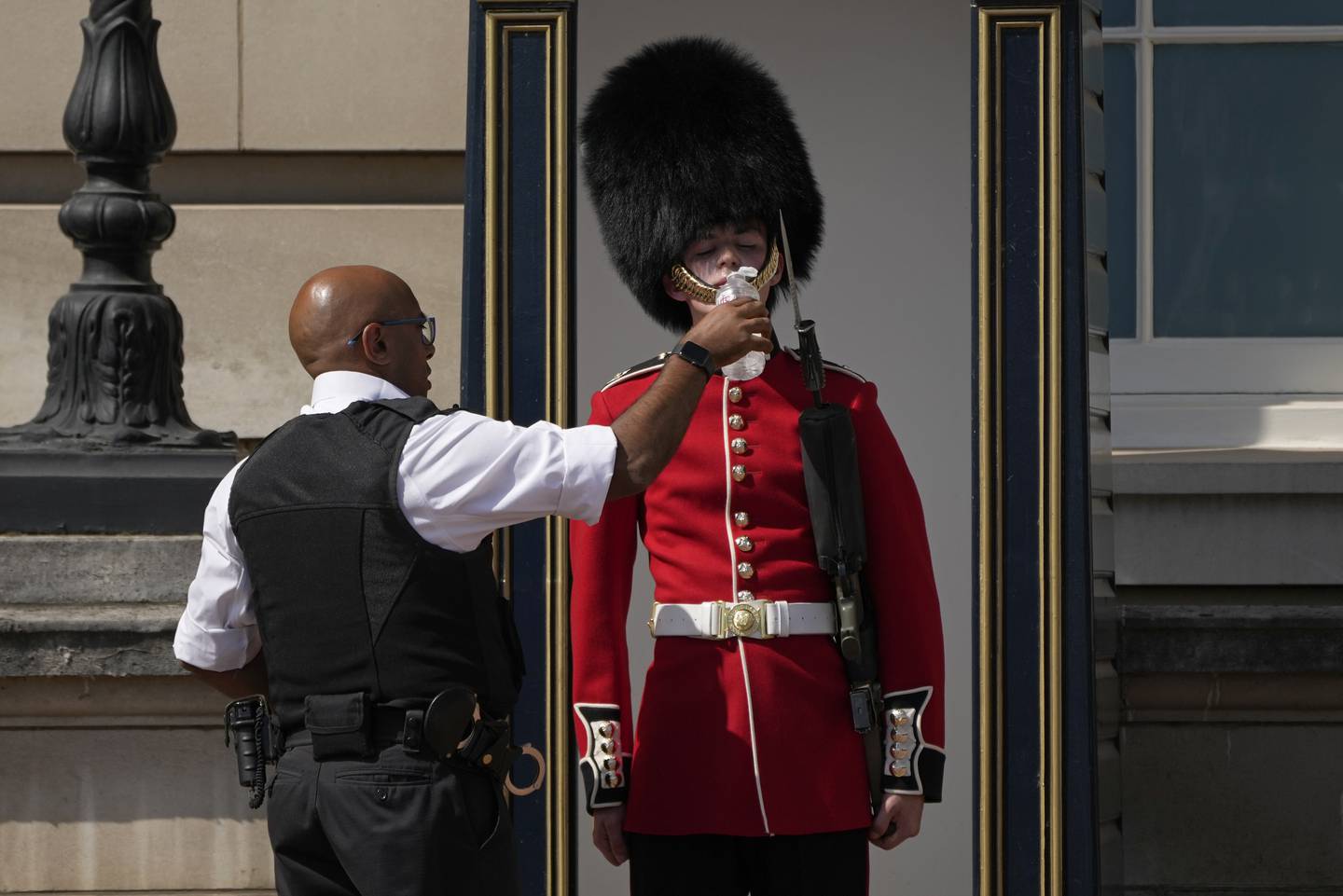 En av vaktene utenfor Buckingham Palace i London fikk vann av en politimann da det ble satt temperaturrekorder i Storbritannia i juli.