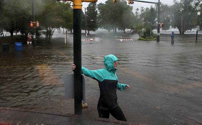 Jamie Thompson walks through flooded sections of East Front Street near Union Point Park in New Bern, N.C. Thursday, Sept. 13, 2018. Hurricane Florence already has inundated coastal streets with ocean water and left tens of thousands without power, and more is to come.  (Gray Whitley/Sun Journal via AP)