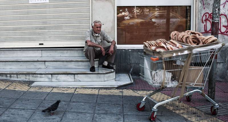 En gateselger tar en hvil i Atens gater. Grekerne som hadde aller lavest inntekt før krisen, fikk sine inntekter redusert med 86 prosent i årene fra 2008 til 2012, ifølge en studie. FOTO: ANGELO TZORTZINIS/NTB SCANPIX