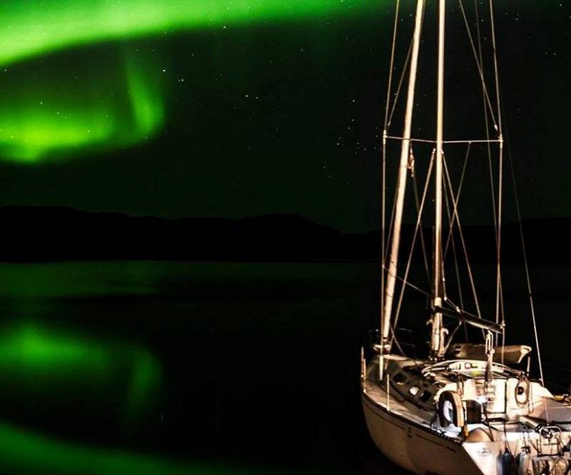 Båt i Nordlys: Her har Johnny Leo Johansen fotografert båten sin mens nordlyset danser over det blikkstille havet.