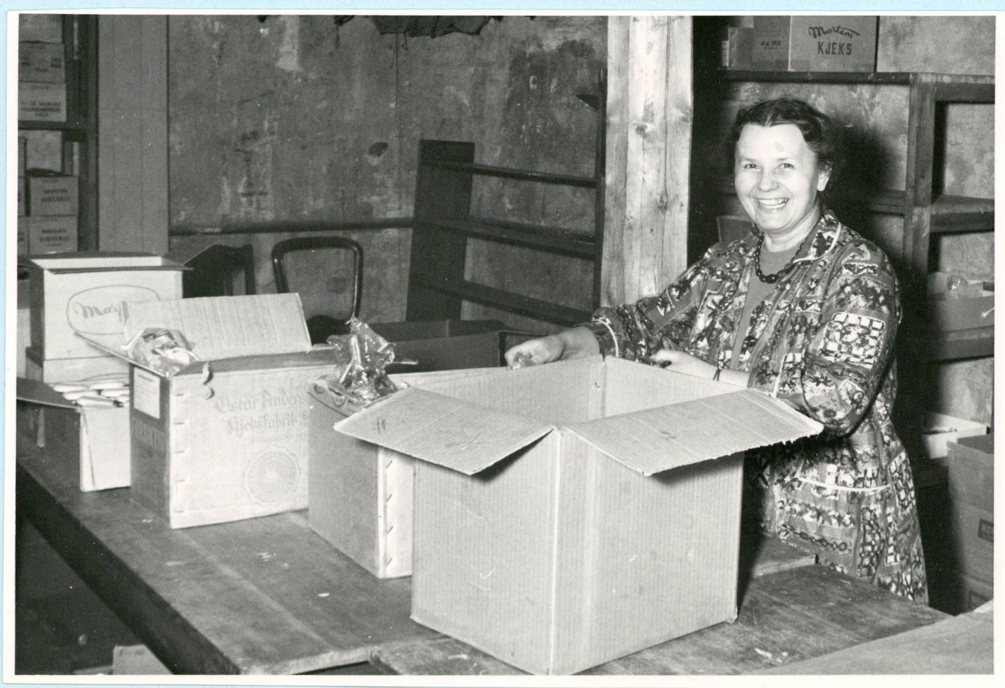 Julegaver 1966 Anna Kvapilova] Daglig leder for Norsk Tsjekkoslovakisk Hjelpeforening, Anna Kvapilova pakker julegaver jula 1966. Anna Kvapilova var selv flyktning og tidligere Ravensbrück-fange.