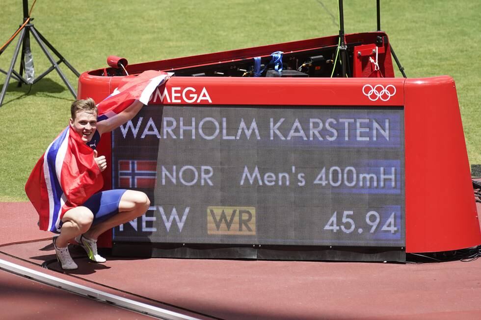 Karsten Warholm poserer ved tavla som viser hans nye rekordtid på 400 meter hekk. Foto: Lise Åserud / NTB