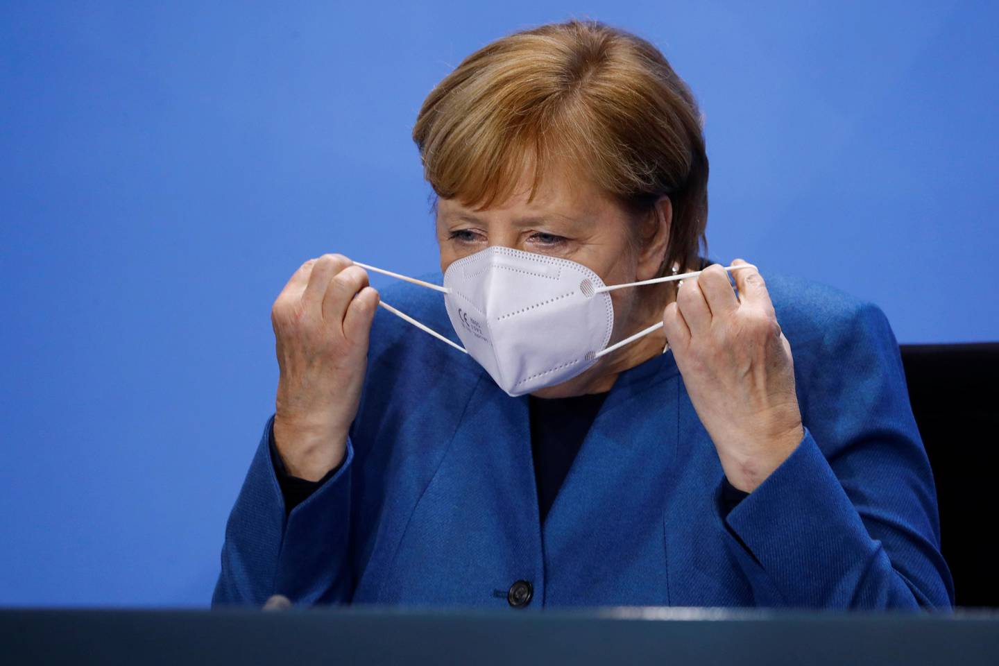 German Chancellor Angela Merkel (CDU) takes off her mask after a press conference at the Chancellery in Berlin, Wednesday, Oct. 28, 2020. Merkel is pressing for a partial lockdown as the number of newly recorded infections in the country hit another record high Wednesday. (Fabrizio Bensch/pool photo via AP)
