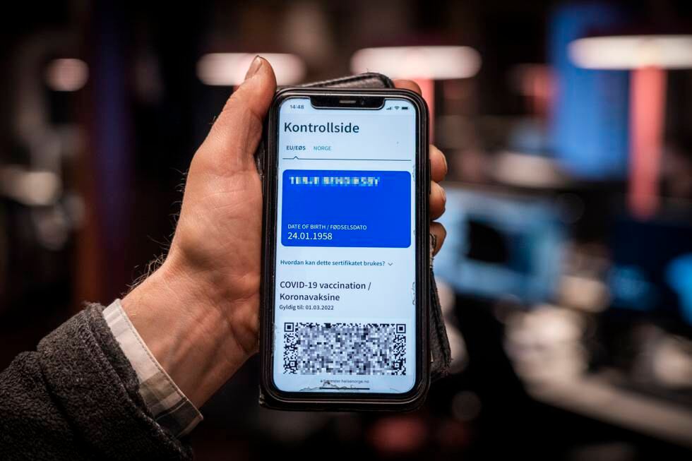 Bildet er av en hånd som holder opp en mobil. Skjermen viser et blått koronapass. Foto: Ole Berg-Rusten / NTB