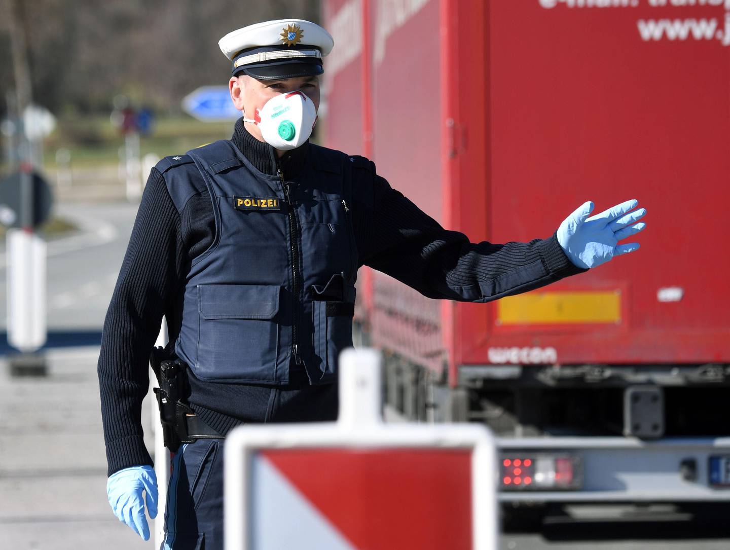 A German police officer, wearing a face mask, stops a driver at the border crossing between Austria and Germany, near the German village of Oberaudorf, as Germany imposes border controls with five countries in a virus fightback, on March 16, 2020. - Germany introduced border controls with Austria, Denmark, France, Luxembourg and Switzerland in a bid to stem the coronavirus outbreak. Only those with a valid reason for travel, like cross-border commuters and delivery drivers, are allowed through, officials said. (Photo by Christof STACHE / AFP)
