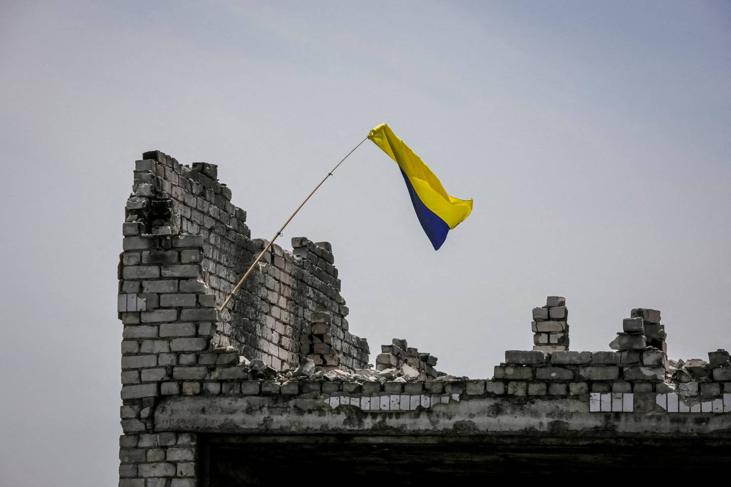 Et ukrainsk flagg vaier i et ødelagt bygg i en nylig gjenerobret landsby langs frontlinja i Donetskregionen 13. juni 2023.